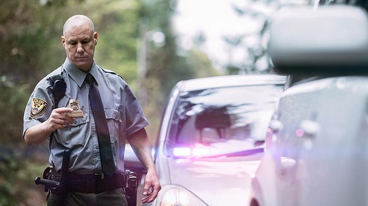 Police officer pulling over car and looking at driver's license.